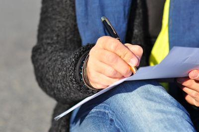 Midsection of woman writing with pen on paper