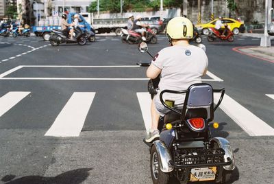 Rear view of people riding motorcycle on road