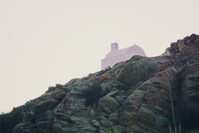 Low angle view of rocks on mountain against clear sky