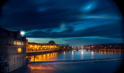 Illuminated buildings by river at night