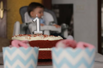 Close-up of cake with baby sitting at background