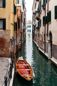 Boat moored in canal amidst buildings