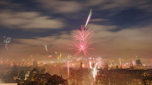 Firework display in city against sky at night