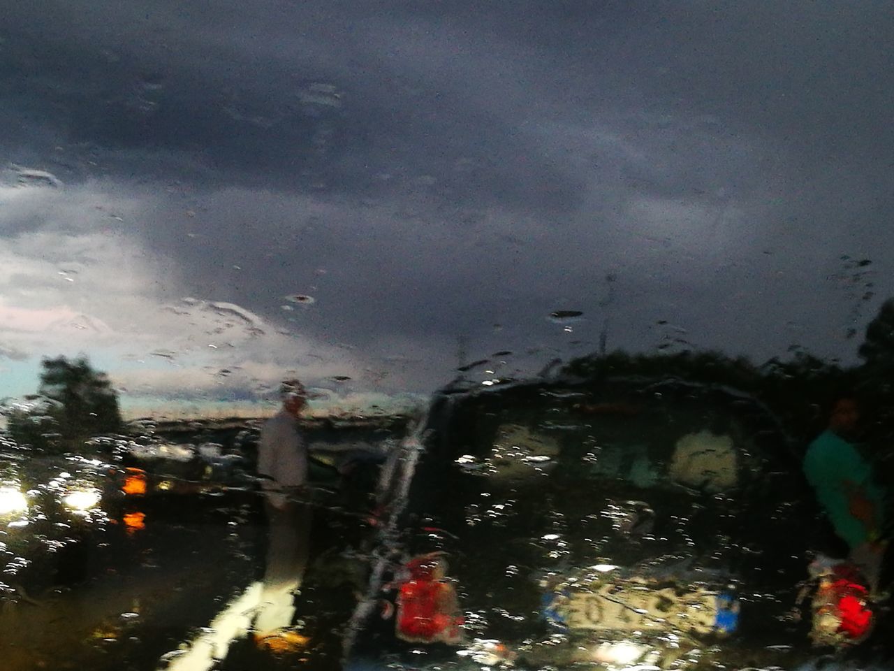 VIEW OF ILLUMINATED STREET SEEN THROUGH WET WINDOW