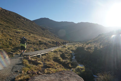 Rear view of man walking on mountain against sky