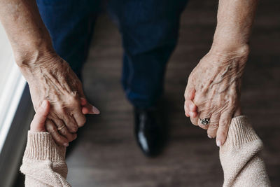 Senior woman holding granddaughter's hands at home