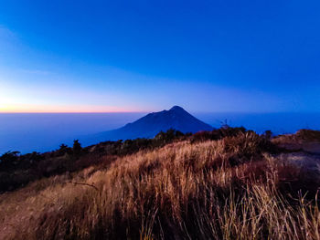 Scenic view of sea and mountains against blue sky