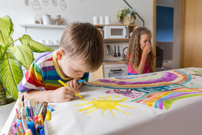 Side view of girl drawing on table