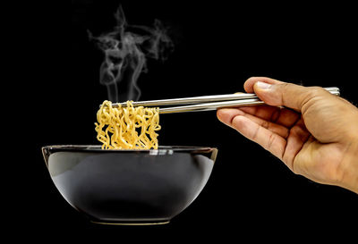 Close-up of person preparing food against black background