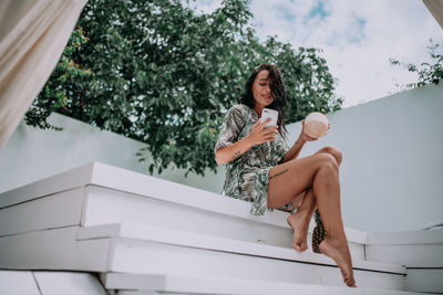 Low angle view of women sitting on wall