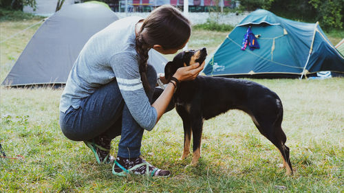 Woman playing with dog on grassy land at campsite