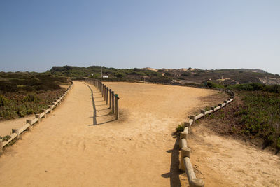 Footpath on field against clear sky