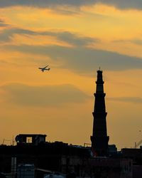 Low angle view of silhouette airplane flying against sky during sunset