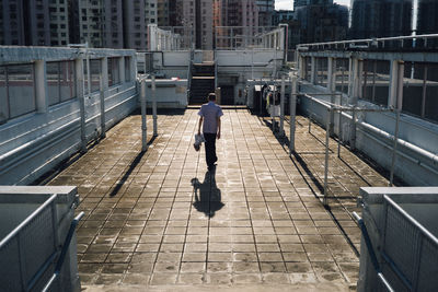 Rear view of man walking on footpath