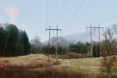 Electricity pylon on field against sky