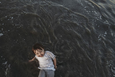 High angle view of happy toddler girl playing in ocean