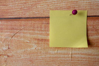 Close-up of yellow adhesive note on wooden table