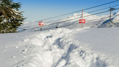 Ski lift over snow covered mountains against sky