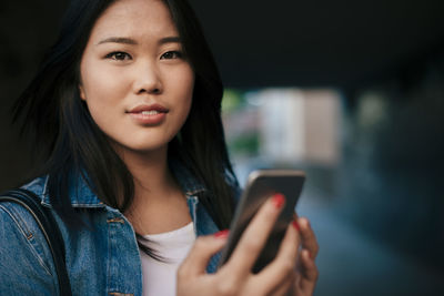 Portrait of teenage girl holding smart phone in city