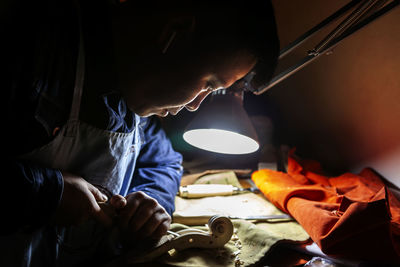 Male craftsman violin maker working on a new violin in the workshop