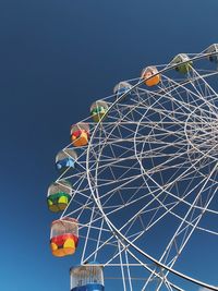 Low angle view of ferris wheel against clear blue sky