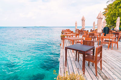 Chairs and table on beach against sky