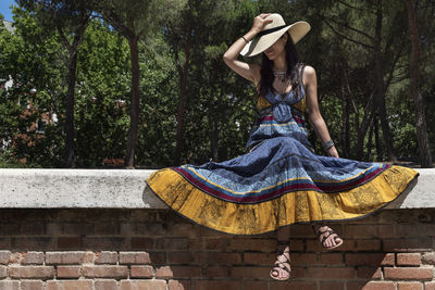 Mid adult woman wearing hat on brick wall during sunny day