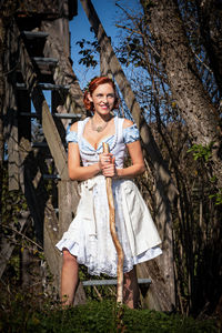 Portrait of smiling young woman against tree