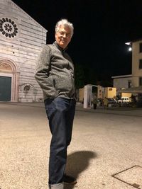 Portrait of man standing against illuminated built structure at night