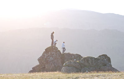 Friends walking on rock against mountain