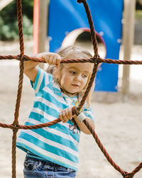 Cute girl holding rope of jungle gym at playground