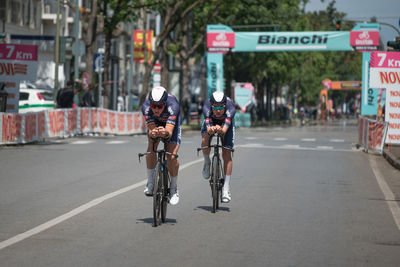 Rear view of people riding bicycle on road in city