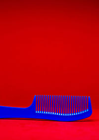 Close-up of blue comb against red background