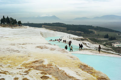 People on travertine pools against sky