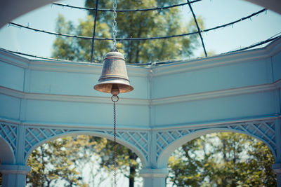Low angle view of bell in gazebo against trees