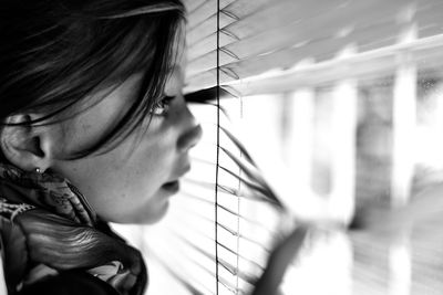 Close-up of girl looking through window