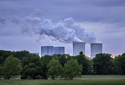 Smoke emitting from factory against sky