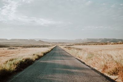 Road amidst field against sky