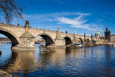 Arch bridge over river against cloudy sky