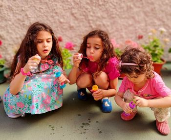 Girls playing with bubbles sitting outdoors