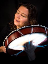 Mature woman playing music against black background