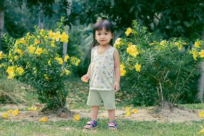 Portrait of girl standing by flowers