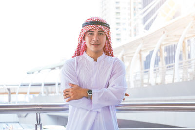 Portrait of young man standing against railing