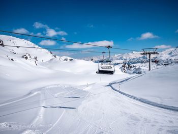 Ski lift over snowcapped mountains against sky