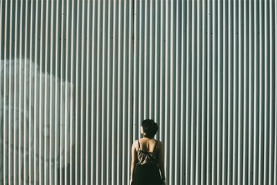 Rear view of woman standing on metal wall
