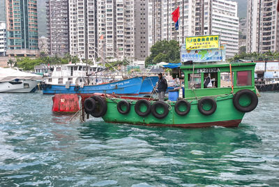 Boats in river by buildings in city