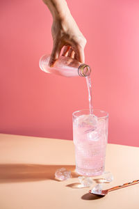 Cropped hand of woman pouring drink in glass