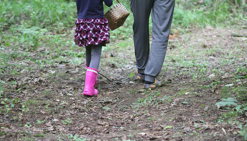 Low section of father and girl standing on field