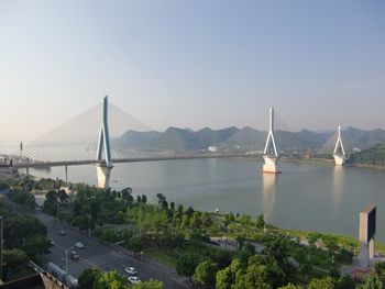 Bridge over river by city against clear sky