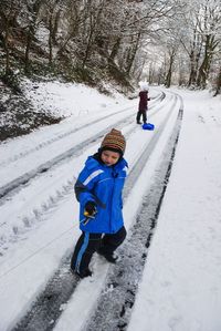 Full length of boy standing on snow covered road